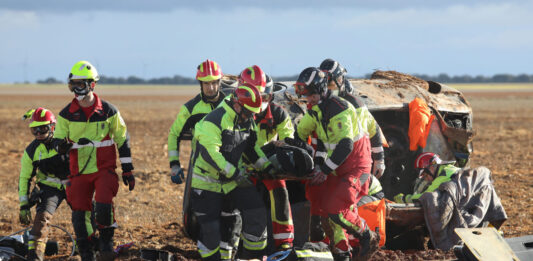 Bomberos de la capital (traje rojo y amarillo) y voluntarios de los parques de la Diputación (traje negro y amarillo) rescatan a una de las heridas en un accidente. / Brágimo (ICAL)