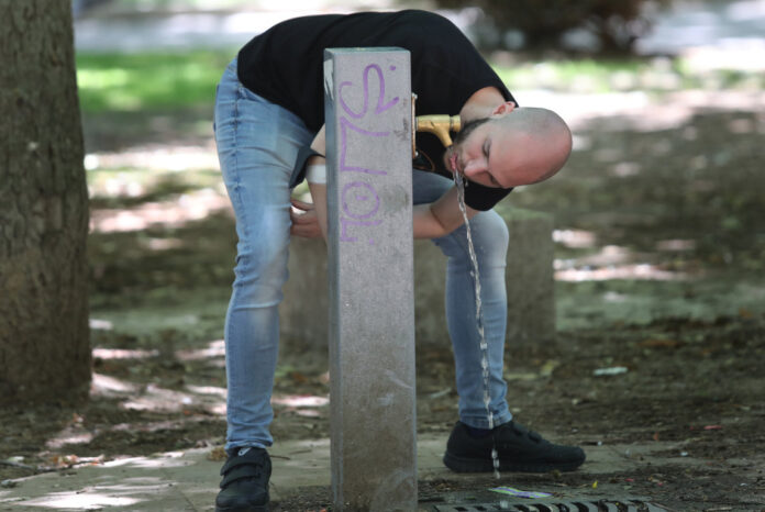 Hombre bebiendo agua de una fuente en Palencia